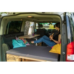 A person sitting on the Vacamod VanBus camping box using the interior setup