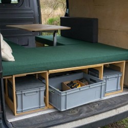 Seitenansicht der braunen VanBus BASIC Campingbox mit ausgeklapptem Essbereich und grüner Matratze