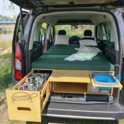 Unfolded KombiVan PREMIUM camping bed platform with green mattresses and slide-out kitchen module