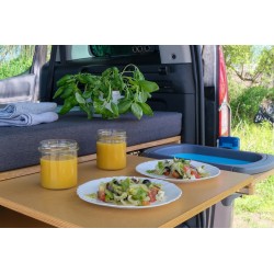 Ausziehbare Arbeitsplatte mit zubereitetem Essen, Säften und der im Hintergrund sichtbaren Wasserpumpe