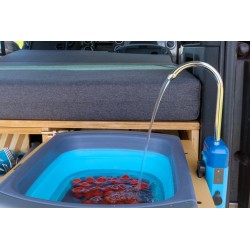 Fresh tomatoes being washed under running water in a portable camping sink