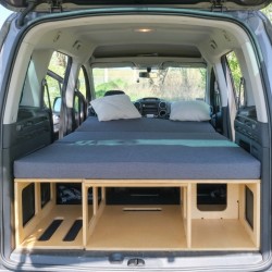 Braune Vacamod KombiVan BASIC Campingbox mit komplett ausgeklappter Bettplattform und angeordneten grauen Matratzen