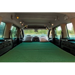 Gemütliches Schlafzimmer im Vacamod Auto-Camper mit einem großen Bett und einer grünen Matratze in einer warmen Atmosphäre