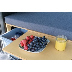 Close-up of an extended pull-out table with snacks and an open Euro crate with kitchen accessories in the Vacamod module