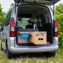 Srebrny van z modułem Vacamod KombiVan SOLO PREMIUM, wysuniętą szufladą kuchenną i szarym materacem.
