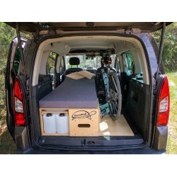 Rear view of a van with unfolded Vacamod SOLO PREMIUM single bed, grey mattress, and a bicycle in the trunk.