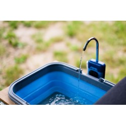 Close-up of water flowing from a rechargeable electric pump faucet into a camping sink.