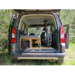 Unfolded Vacamod SOLO BASIC single bed on the left side, grey mattresses, and a bicycle in a van trunk.